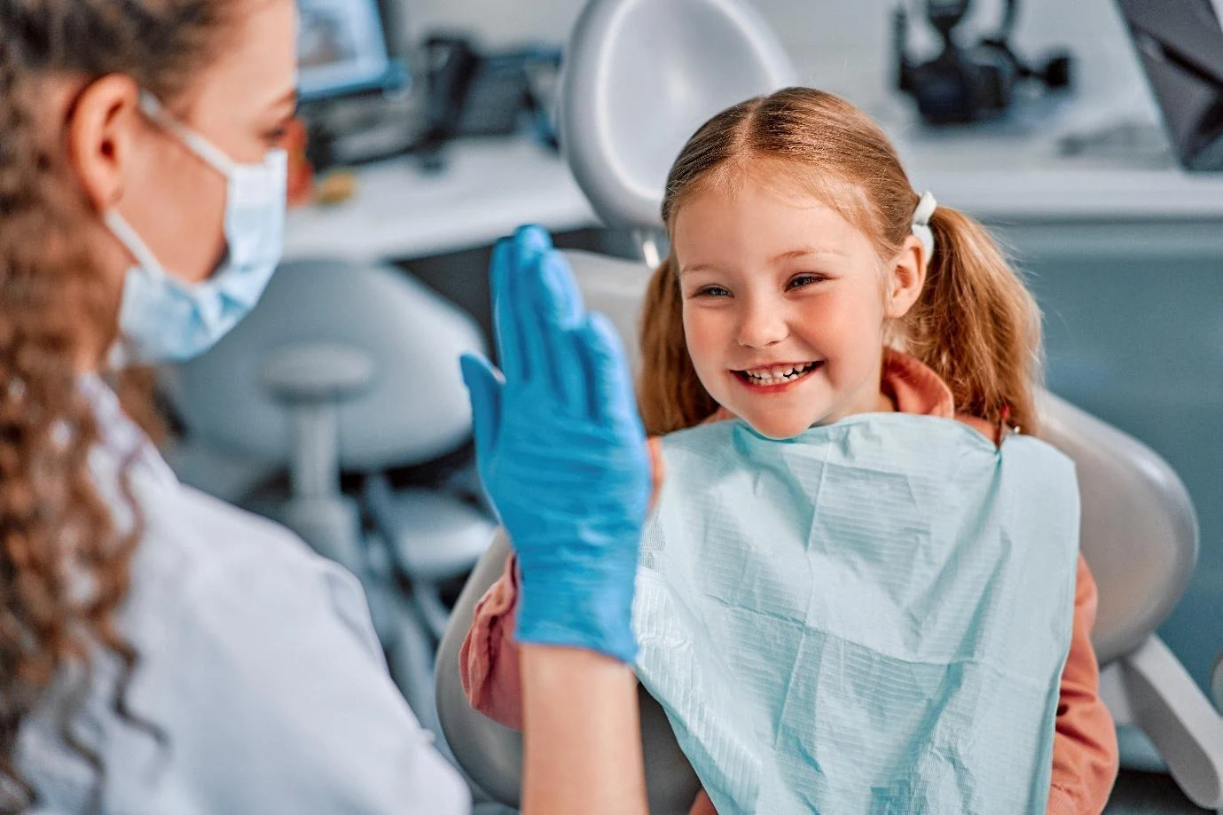 A smiling young girl giving a high five at the dentist